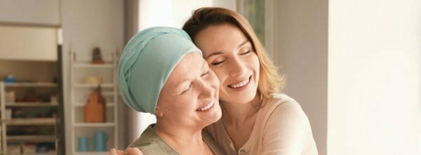 Smiling cancer patient and supportive loved one hugging, representing financial assistance for esophageal cancer through grants and charities.