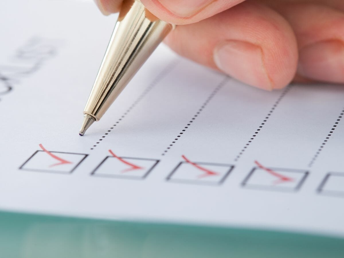 A hand holds a pen, checking boxes on a checklist, symbolizing the detailed steps and planning involved in managing a terminal cancer diagnosis.