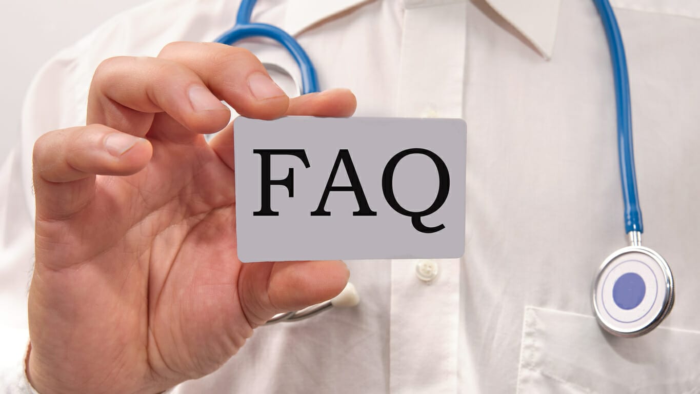 Doctor holding a card with 'FAQ' text, symbolizing frequently asked questions about medical or healthcare topics.