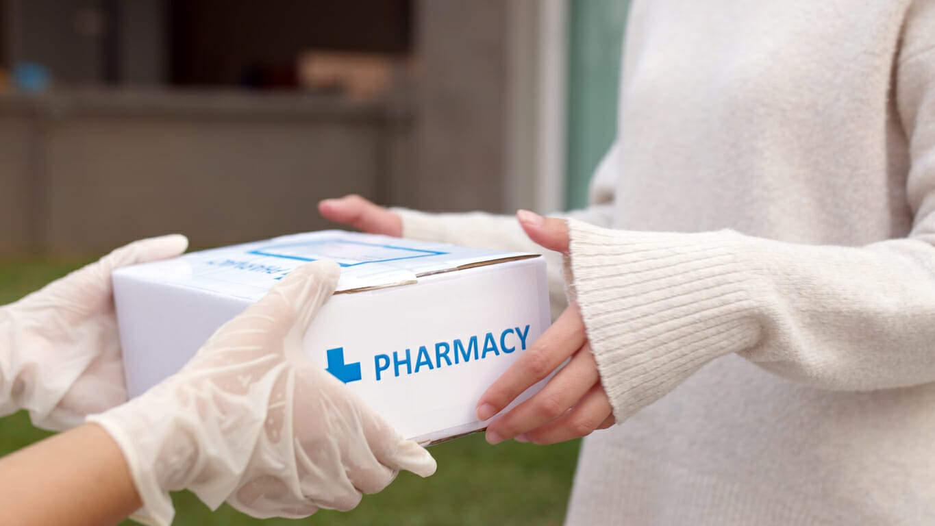 Person receiving a pharmacy package, symbolizing financial assistance for leukemia patients.