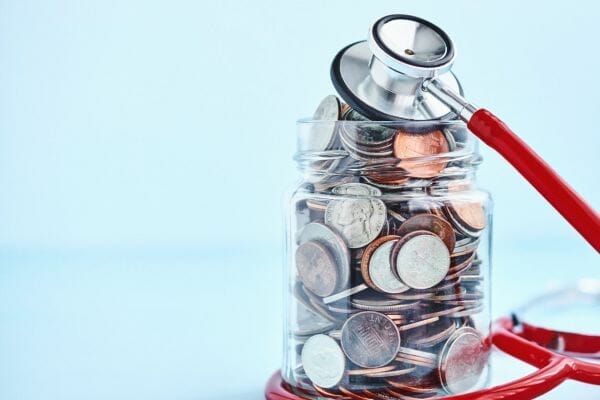 Jar filled with coins and a stethoscope symbolizing financial aid and healthcare support in North Carolina.