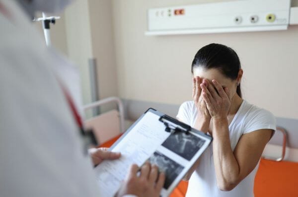 Doctor showing medical results to a distressed woman, highlighting the need for leiomyosarcoma financial assistance.