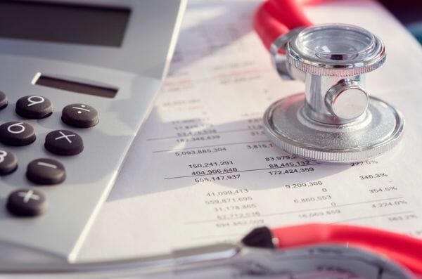 Calculator and stethoscope on financial documents, representing financial assistance for leiomyosarcoma patients.