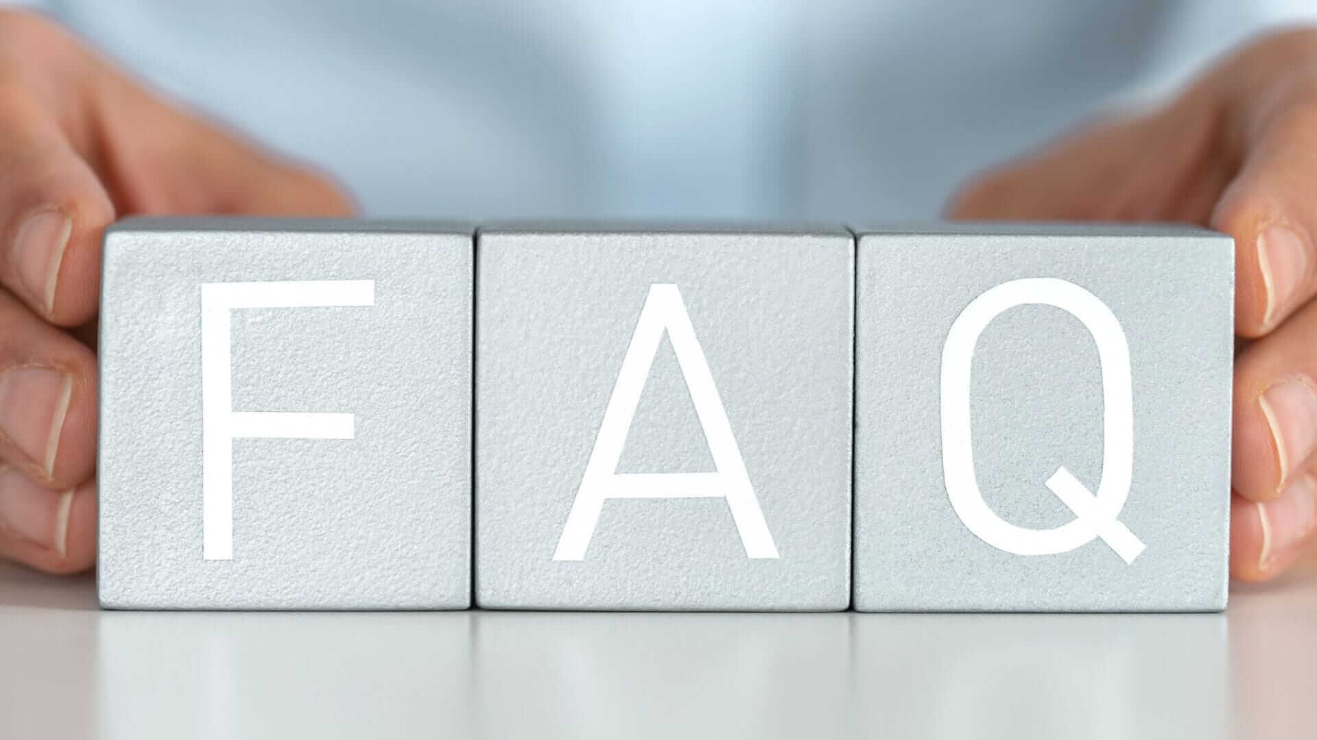 Hands holding three metallic blocks aligned horizontally with the letters 'F', 'A', and 'Q' on them, representing frequently asked questions about liver cancer treatment costs.